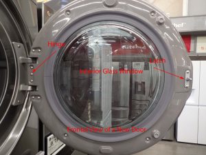 Figure #1: Photograph of a representative new clothes washer door. The door glass is a 5mm thick “cupped shaped” piece of heat strengthened glass. The convex portion of the glass reaches into the washer.